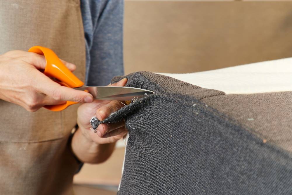 A worker cutting custom upholstery for a chair near Los Angeles, CA